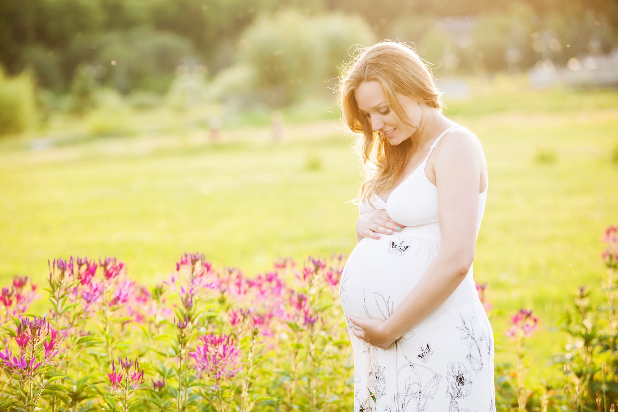 Pregnancy Life|young-pregnant-woman-looking-at-her-belly-in-park